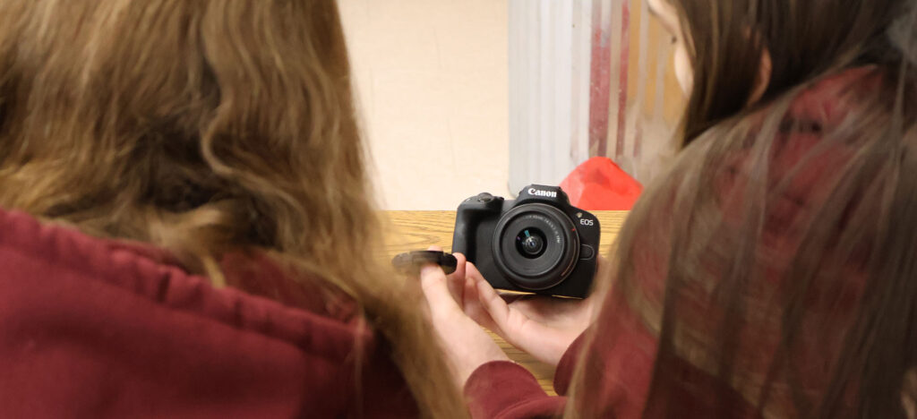 two female students looking at a canon camera in class