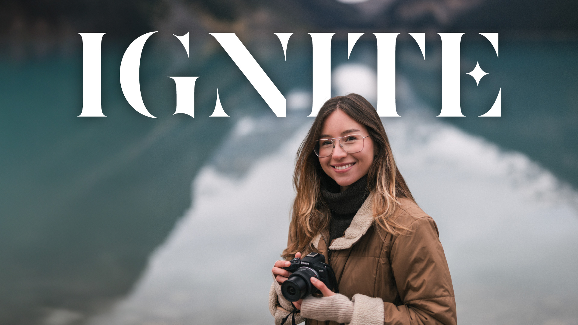 woman holding a canon camera with mountains in the background