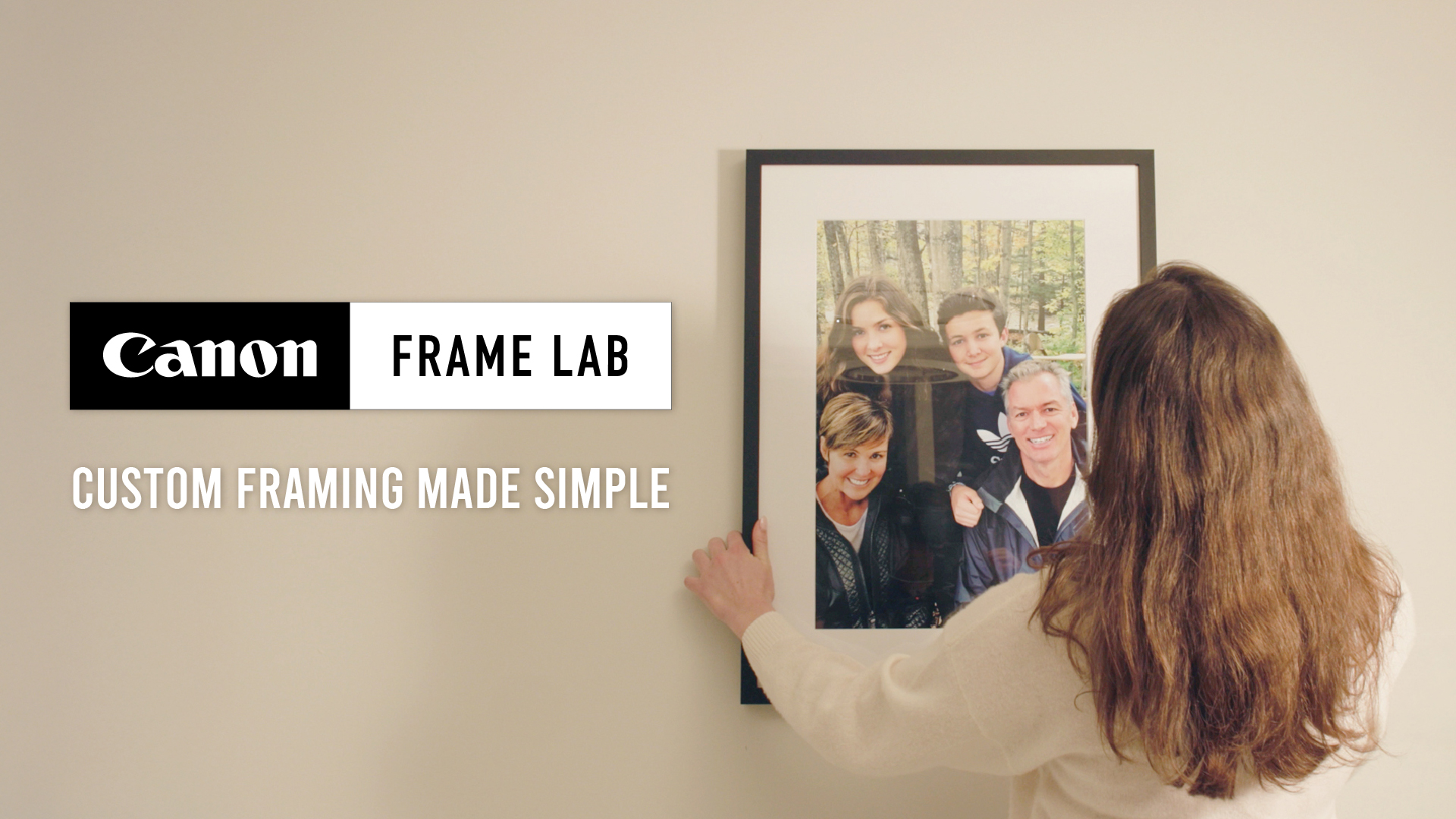 woman putting up a frame lab frame of her family on the wall
