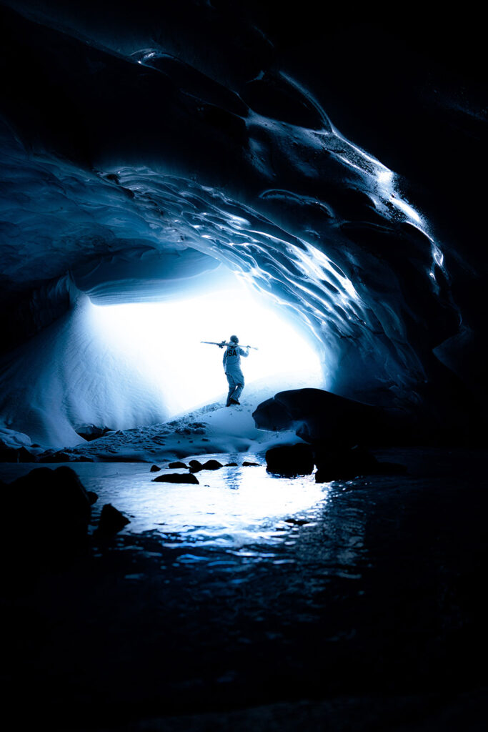 snowboarder standing in front of a cave entrance