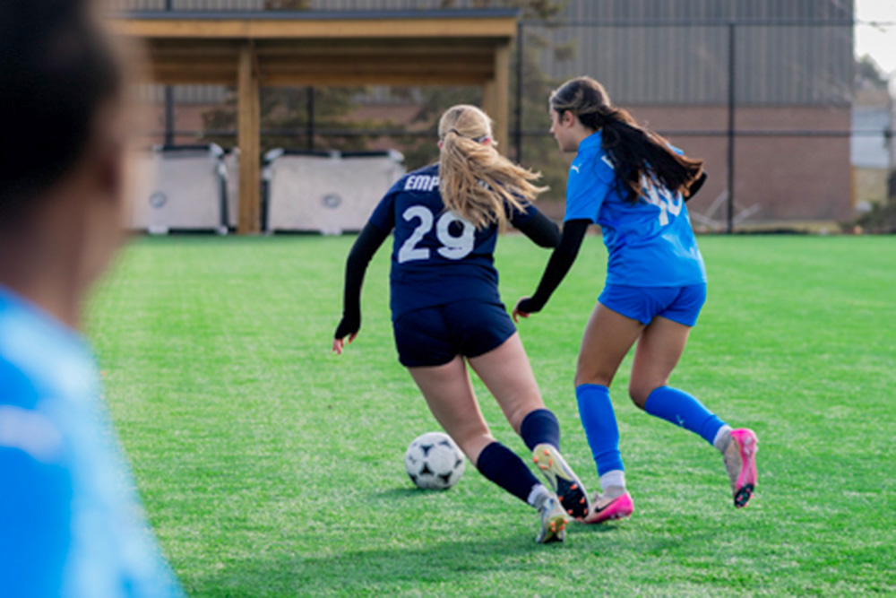 2 girls fighting for the ball in soccer