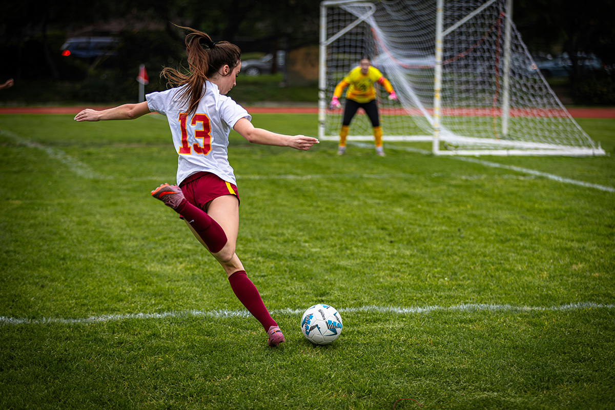 female soccer player kicking a soccer ball towards the goal