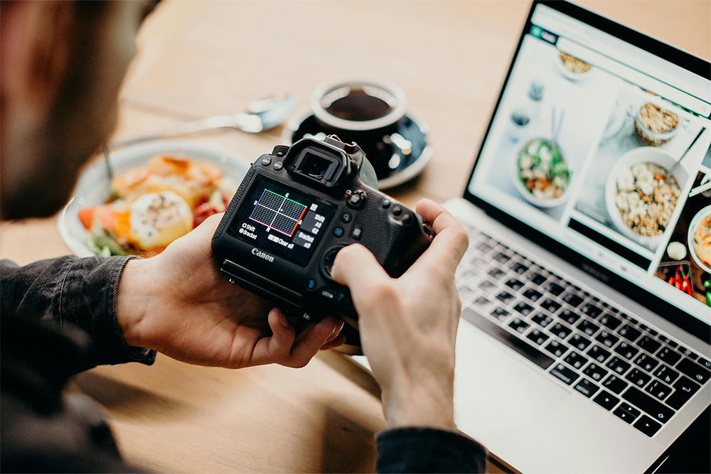 man checking camera settings in front of his laptop